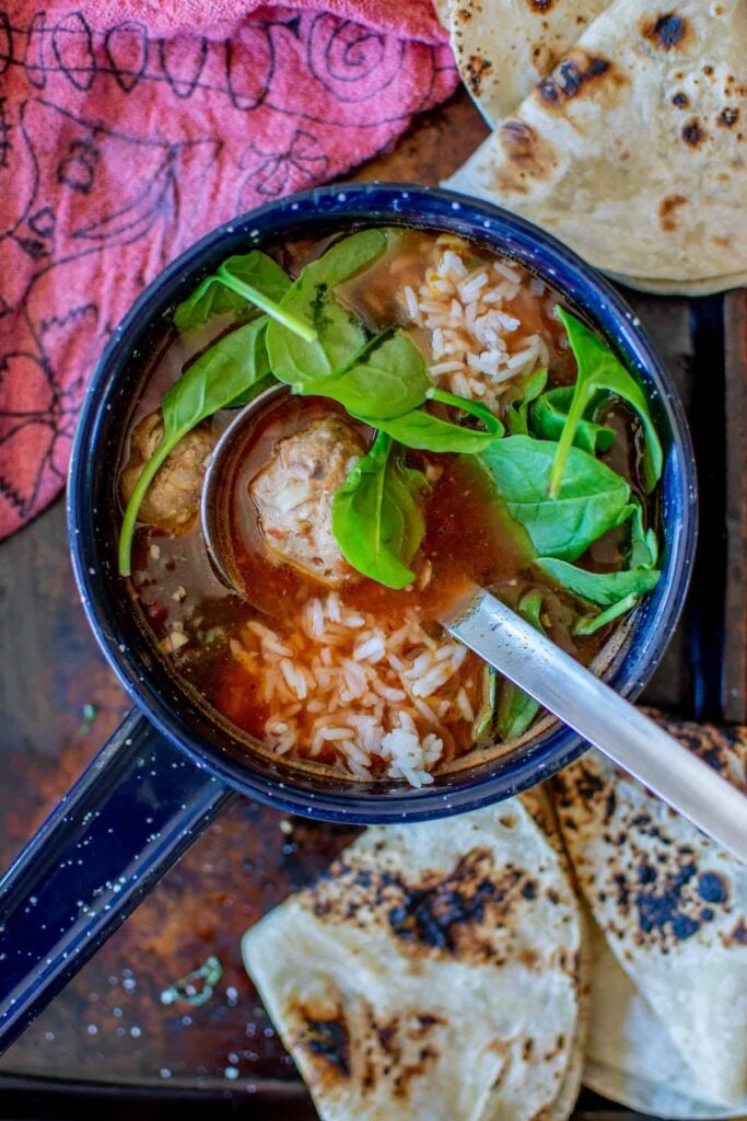 a blue pot with meatball soup in it
