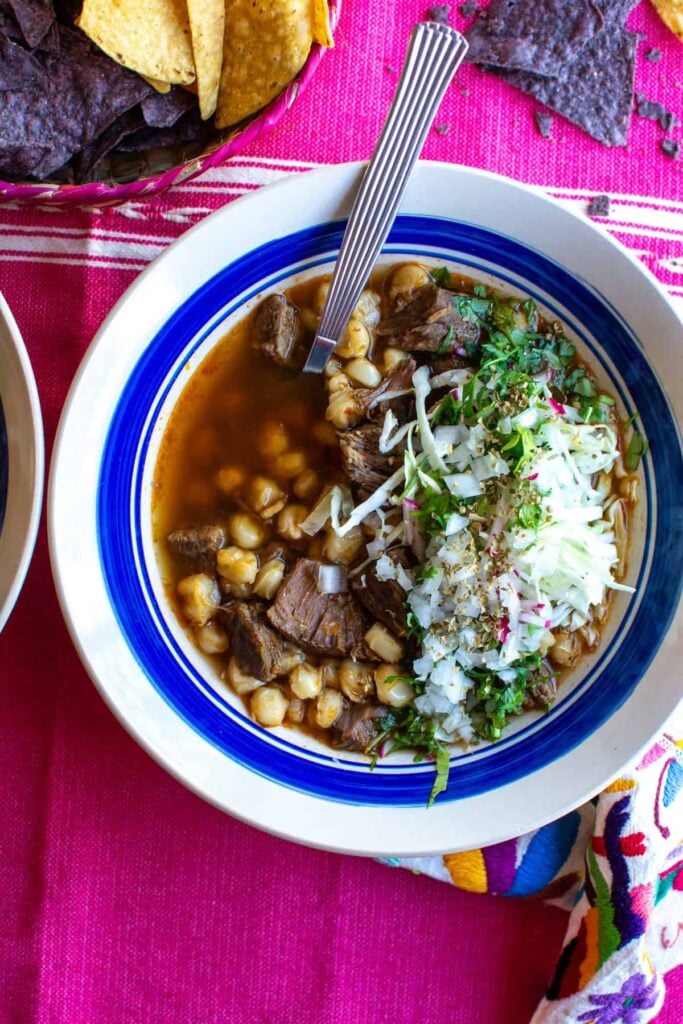 a bowl of pozole on a pink cloth