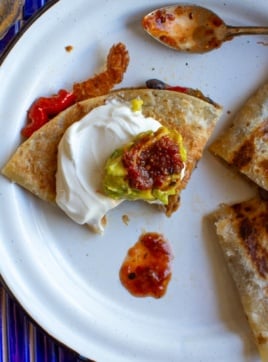 A quarter of a chicken quesadilla with sour cream on top