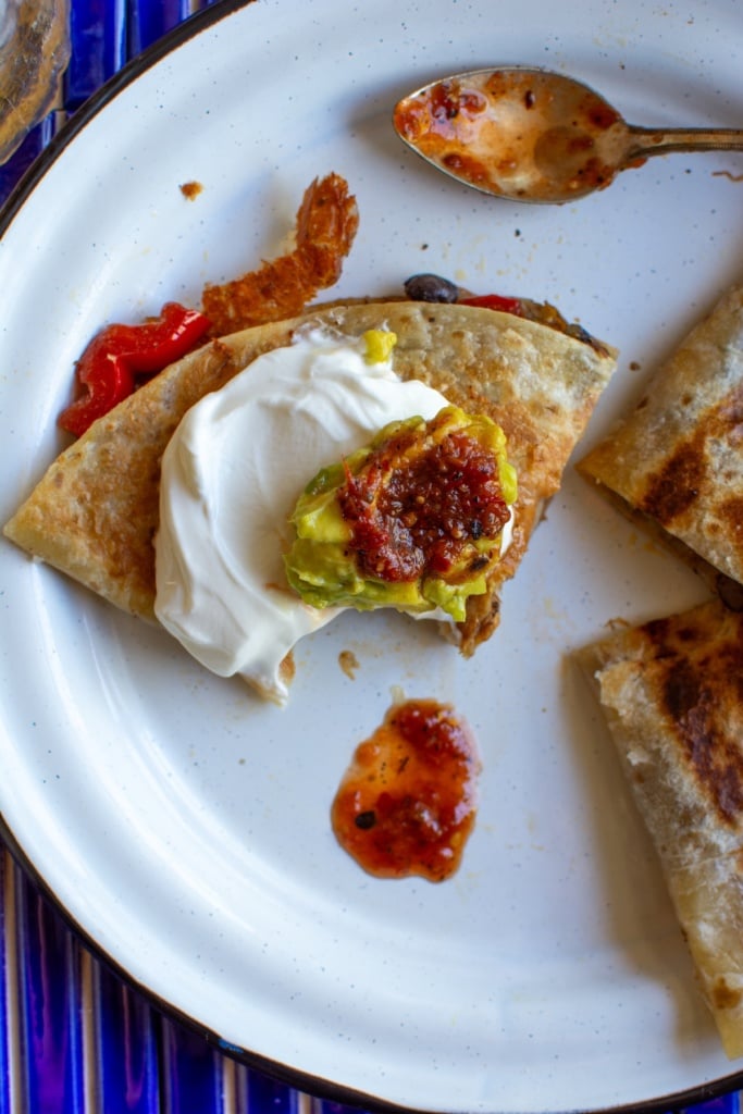 A quarter of a chicken quesadilla with sour cream on top