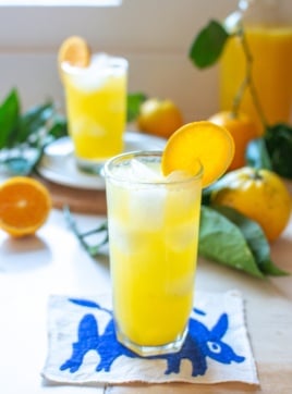 two glasses of orange agua fresca with an orange slice