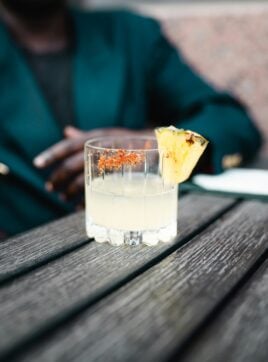 A woman sitting next to a glass of tequila