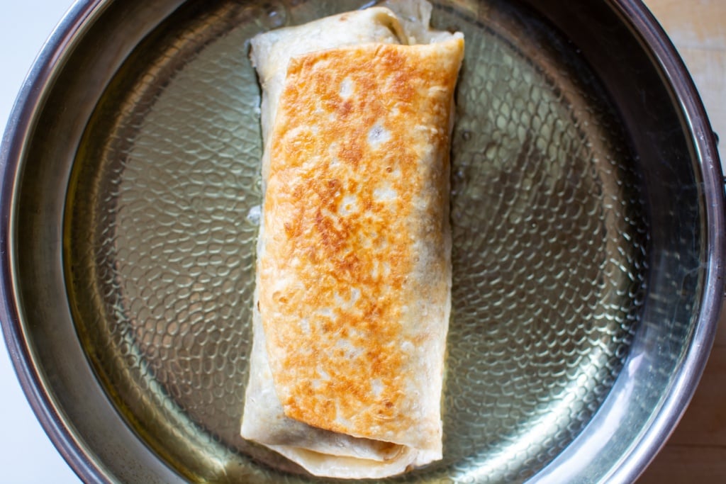 a chimichanga frying in a pan