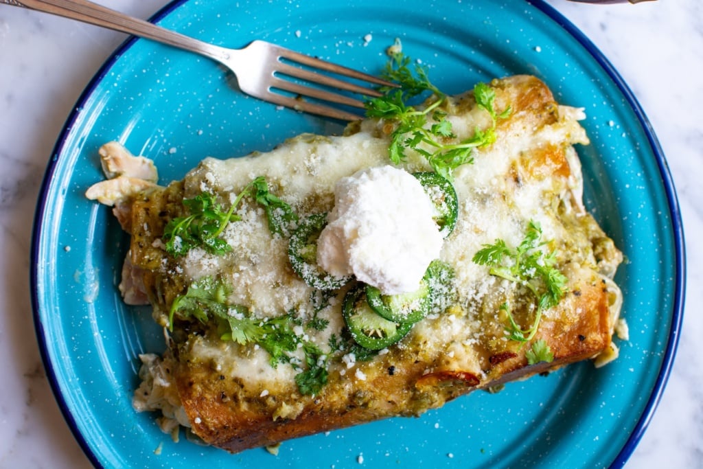 chicken enchiladas topped with sour cream on a blue plate