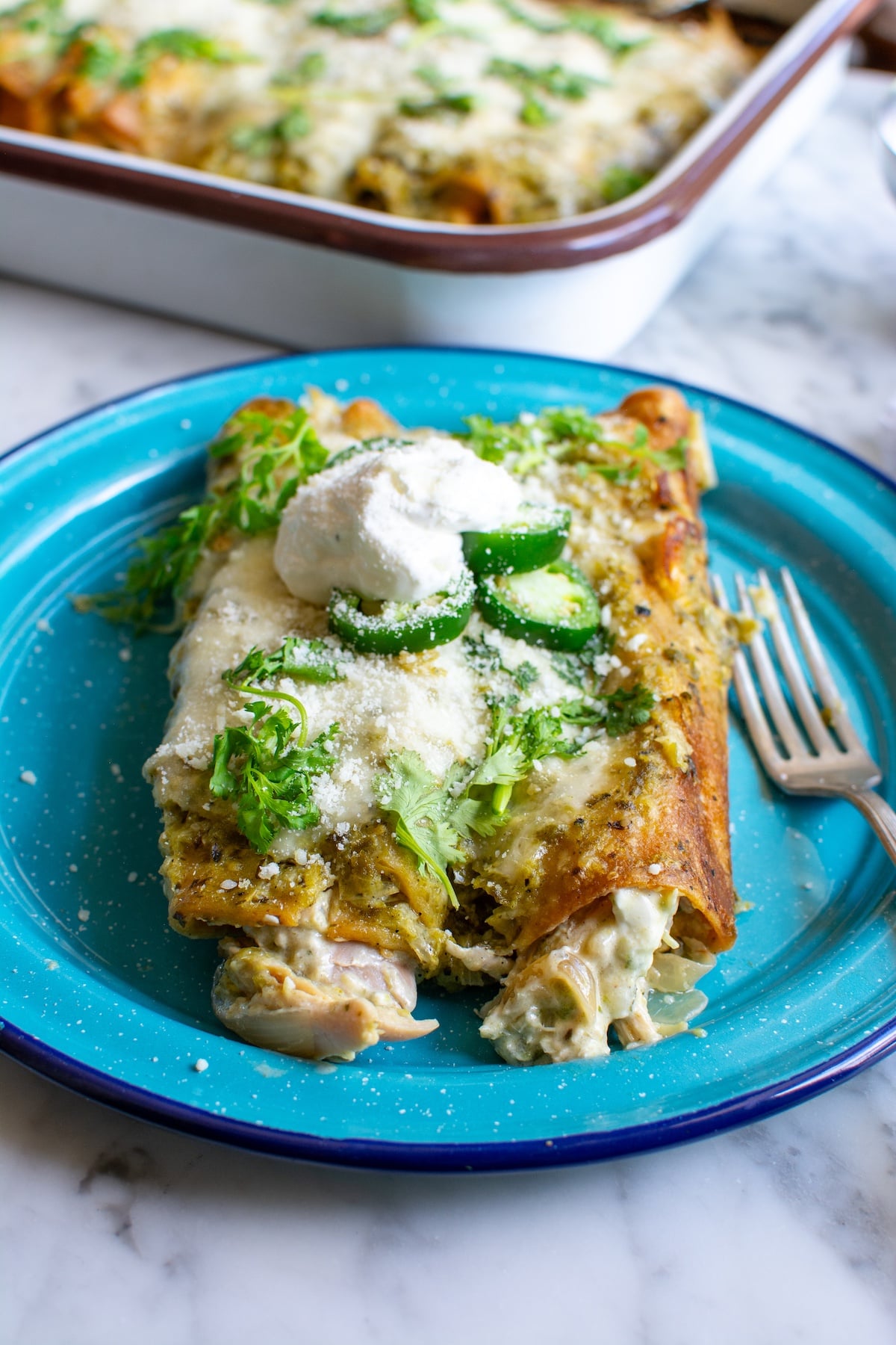 enchiladas on a blue plate with a fork
