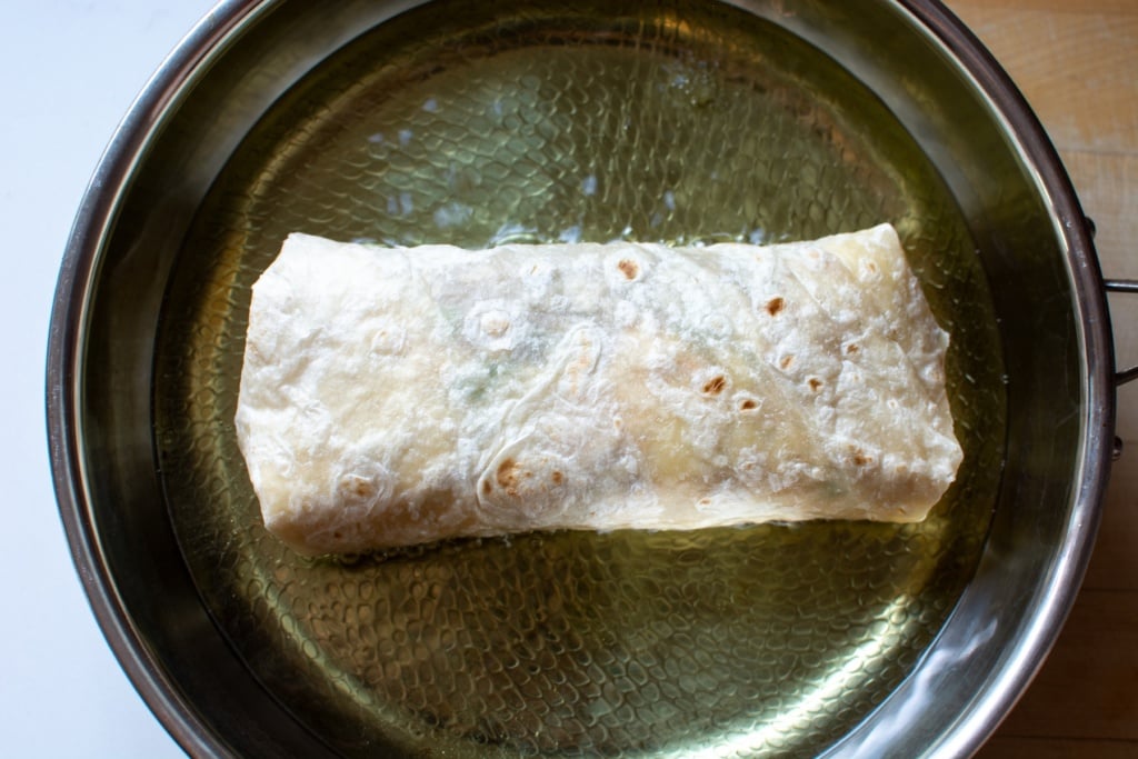 a chimichanga frying in a pan