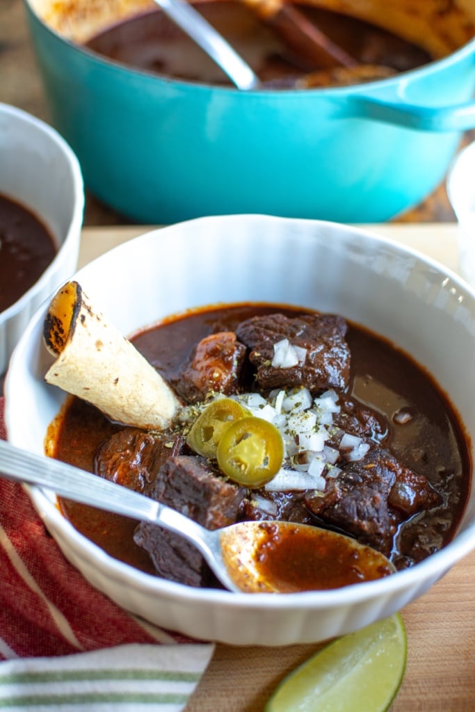 a bowl of red chile next to a blue pot of chili