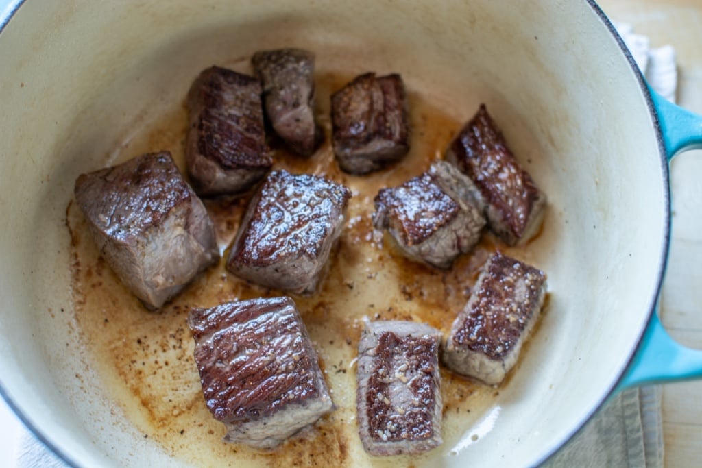 the pieces of beef in a pot browning