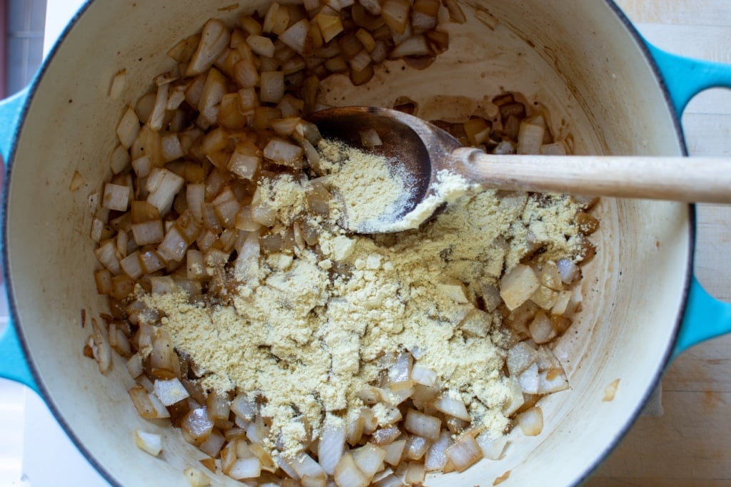 onions and masa harina with a spoon in a pot