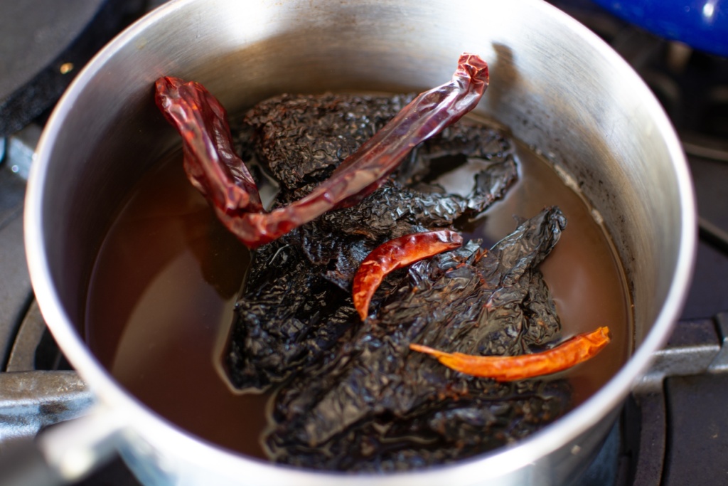 red chiles soaking in a pan in beef broth