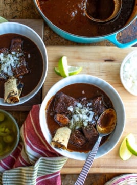 two bowls of red chili with chopped onions on top