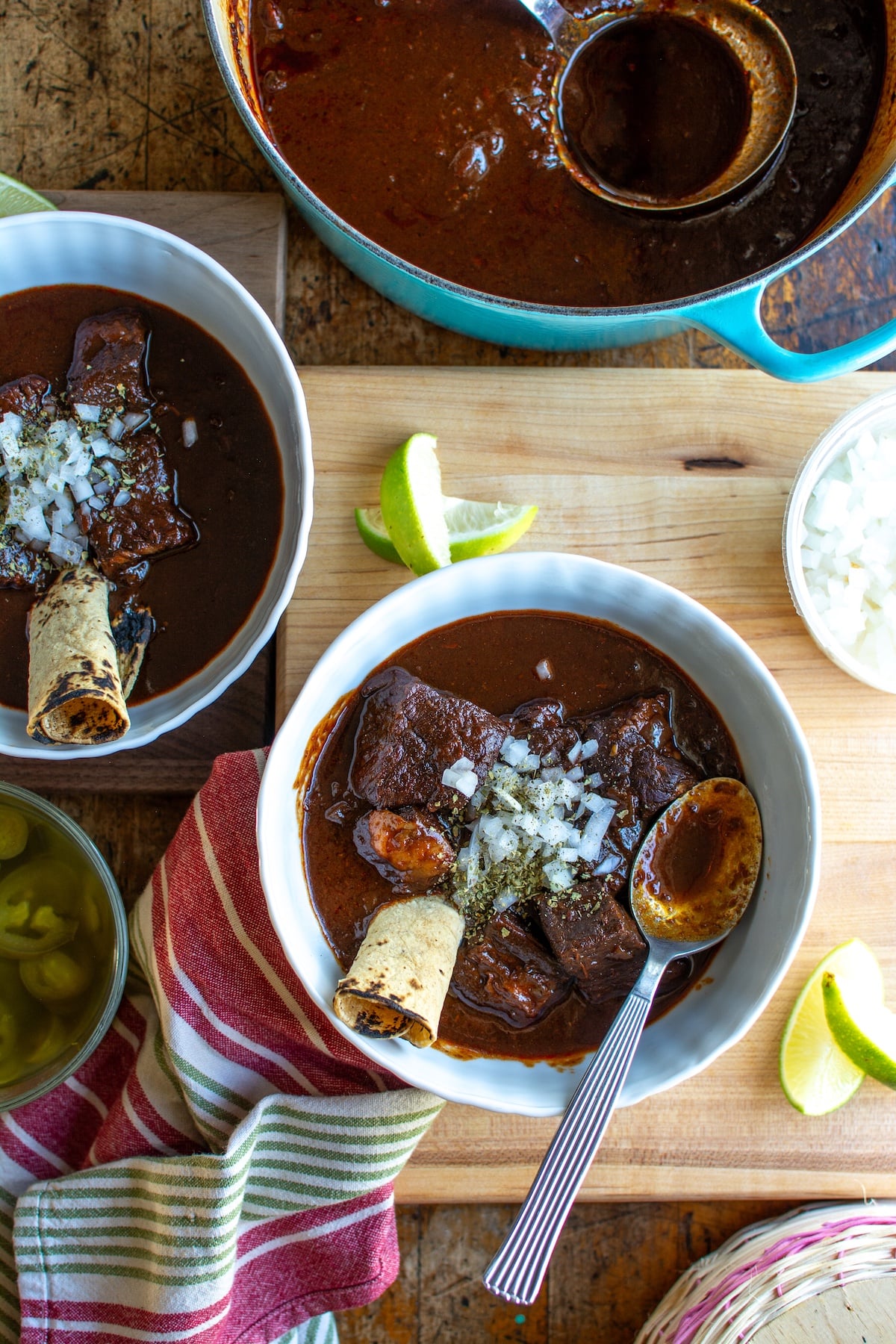 two bowls of red chili with chopped onions on top