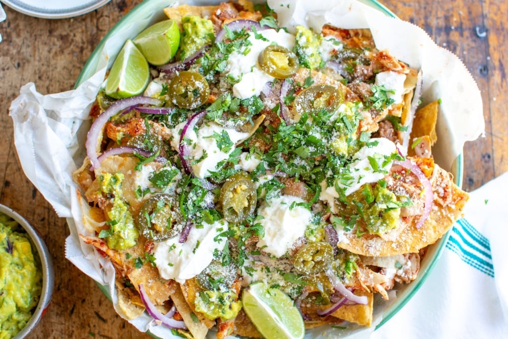 shredded chicken nachos in a dish topped with sour cream