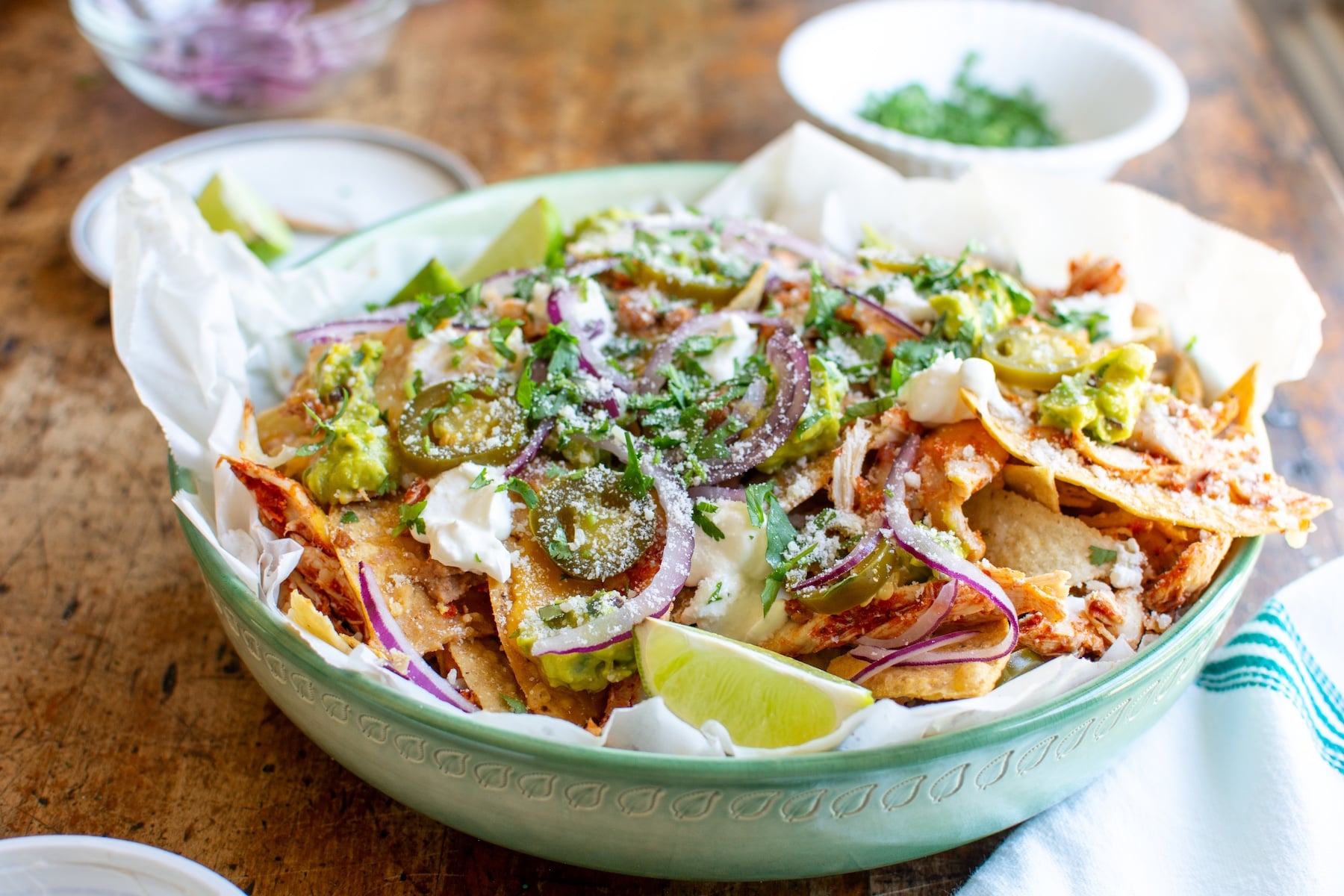a green dish full of shredded chicken nachos