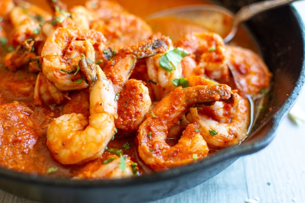 shrimp in red sauce in a black skillet.