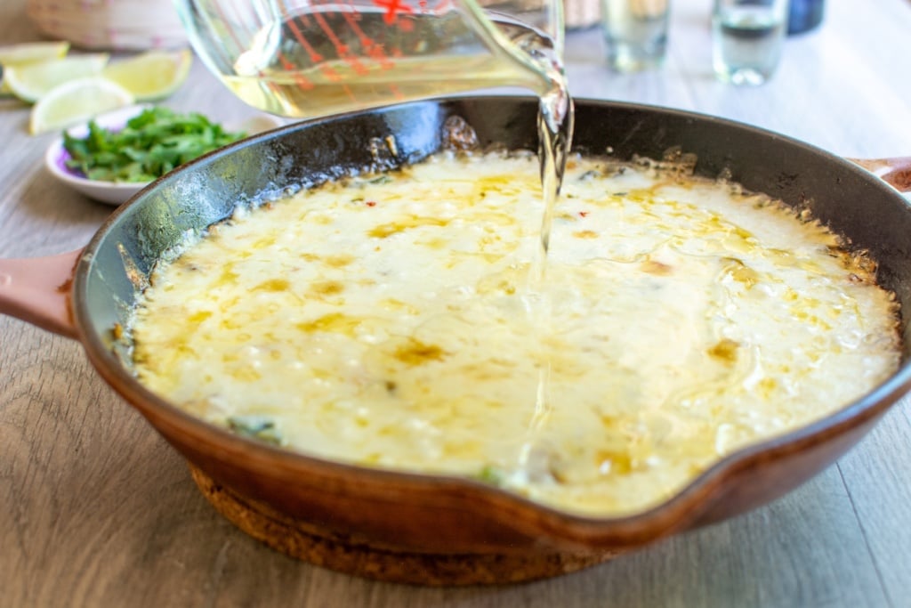 pouring tequila on top of melted cheese