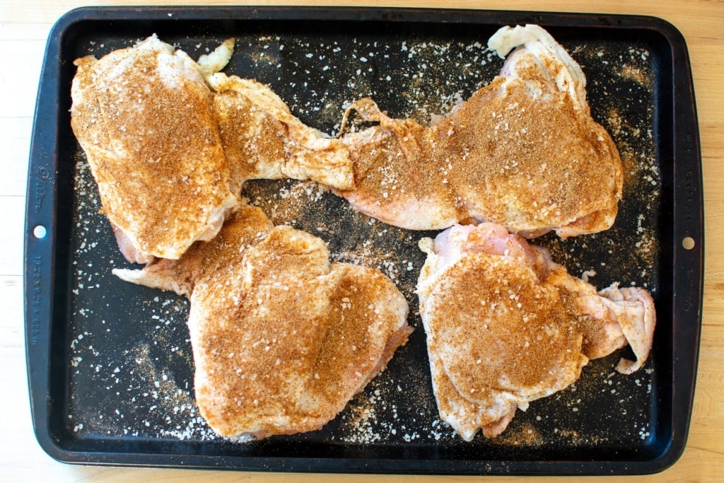 chicken thighs seasoned on a baking sheet